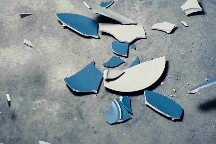A broken blue plate on a hard floor