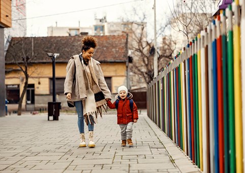 Parent and child walking next to colourful fence
