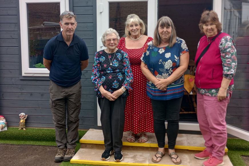 Five people standing together in front of a community hub