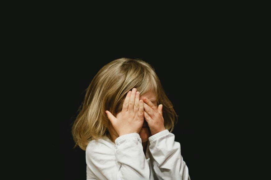 A young child covering their eyes