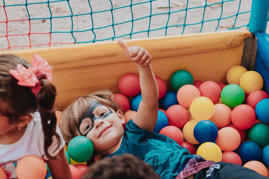 A boy giving a thumbs up in a ballpit