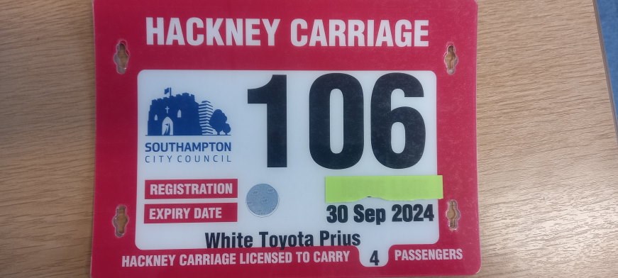 A hackney carriage plate example. This should typically show a large number, the vehicle registration, expiry date, colour, make, and model of the vehicle. It also shows the number of passengers the vehicle can carry.