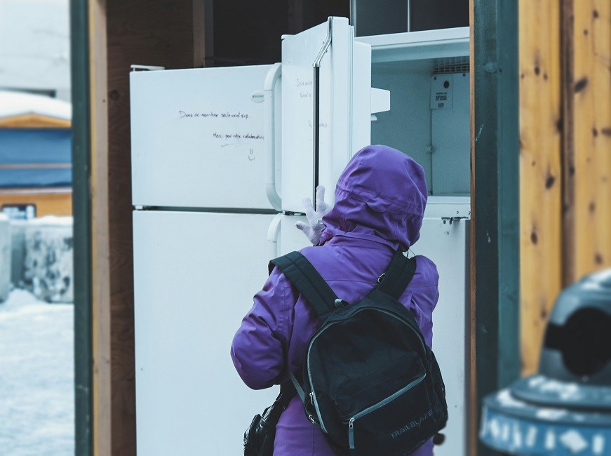 Child in purple hoodie checking empty freezer