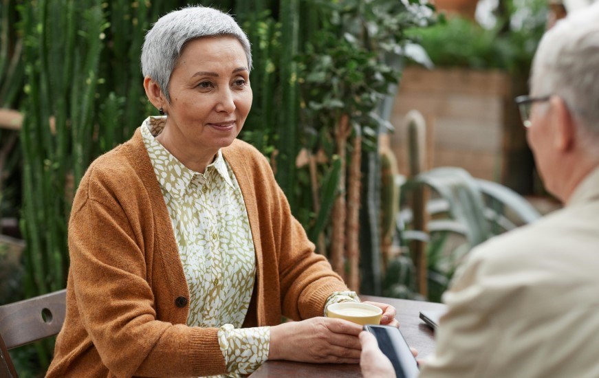 Older woman with a coffee talking to someone