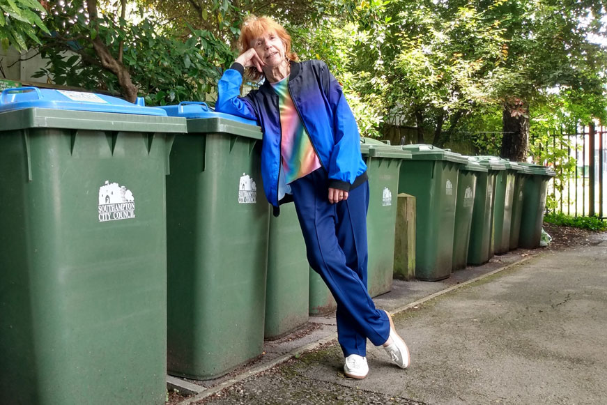 A woman leaning on a recycling bin