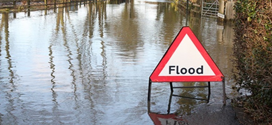 A flood warning sign surrounded by water