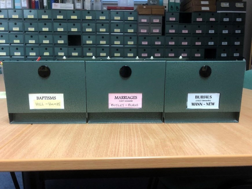 Index trays for baptisms, marriages, and burials, organised alphabetically according to surname. The indexes are available to browse in our reading room.